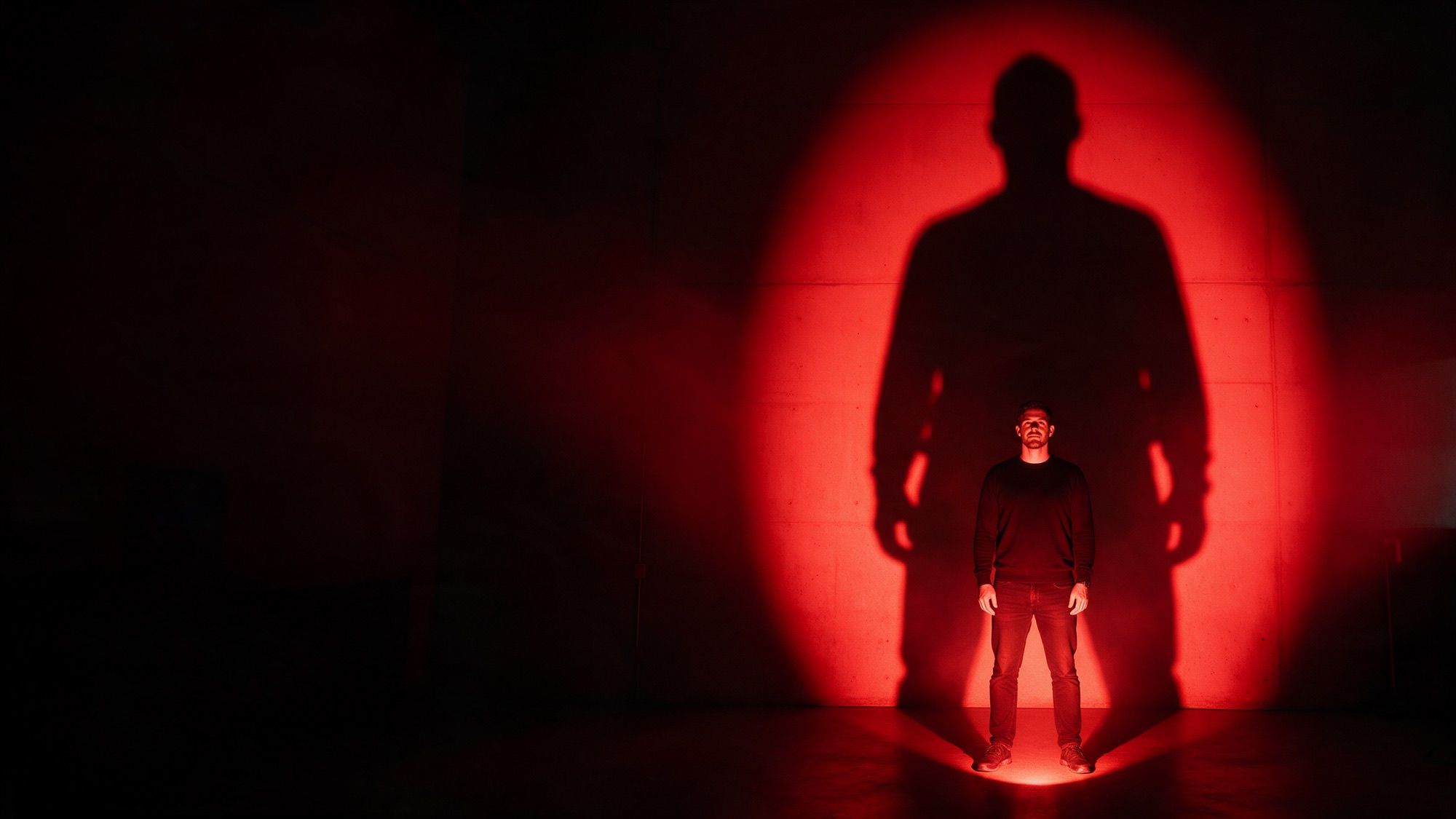 A founder in a red spotlight casting a shadow ten times their size